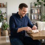 Homme souriant déballant un cadeau dans un appartement moderne